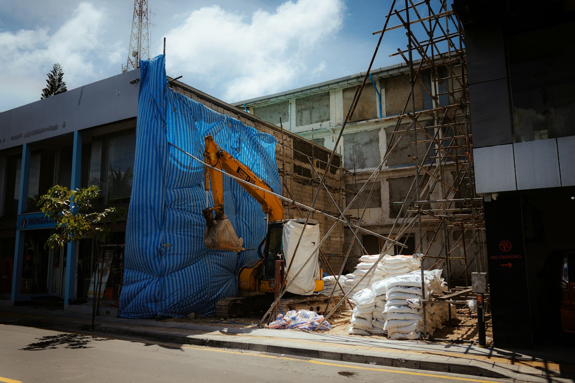 An excavator and scaffolding at a building under construction