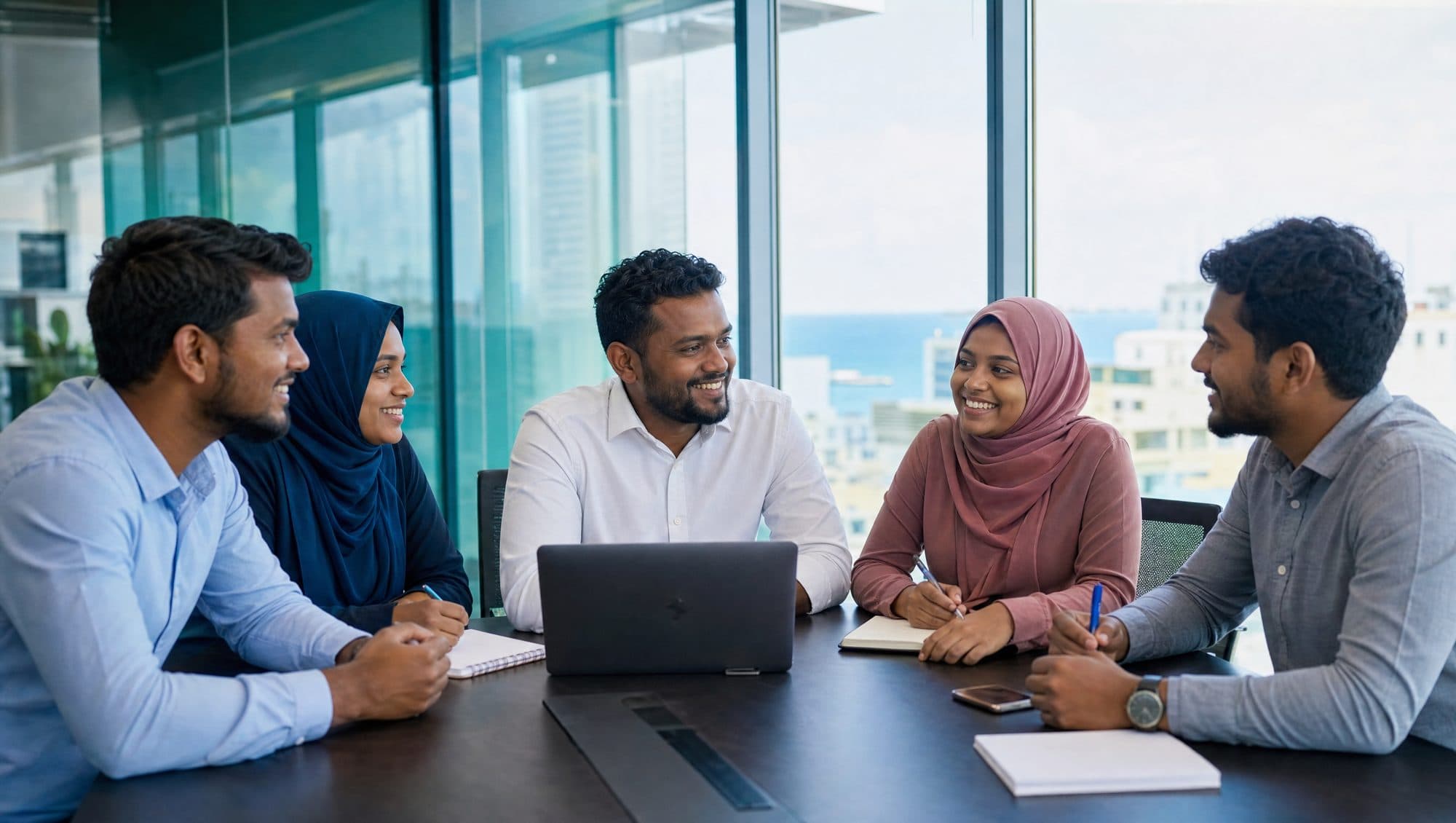 Five colleagues talking around a meeting table in an office overlooking the sea