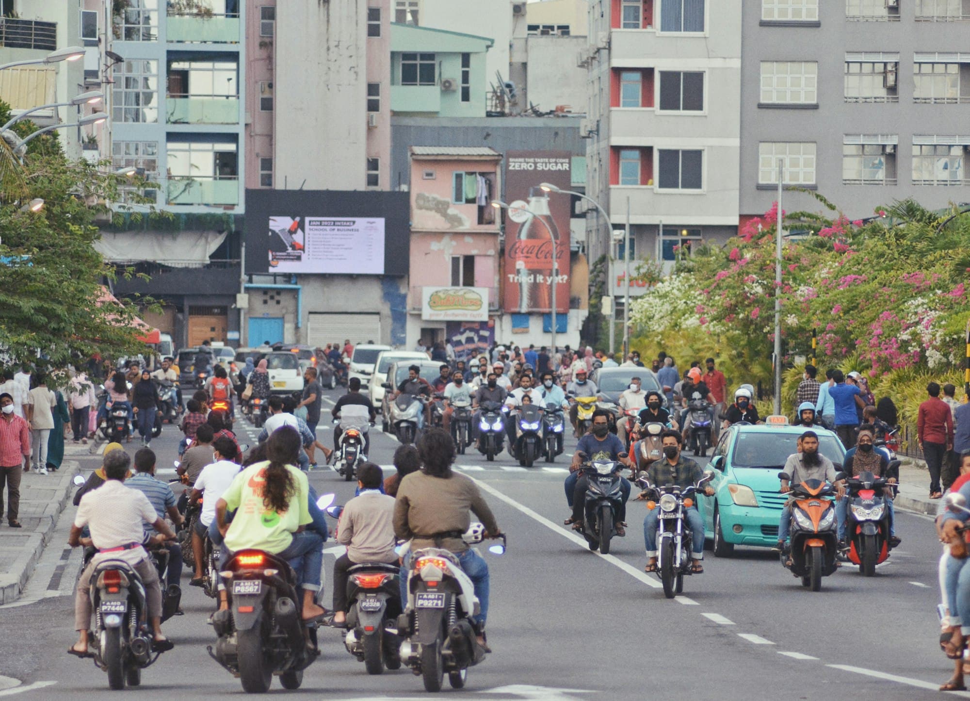 Motorbikes and cars on a busy street in Malé