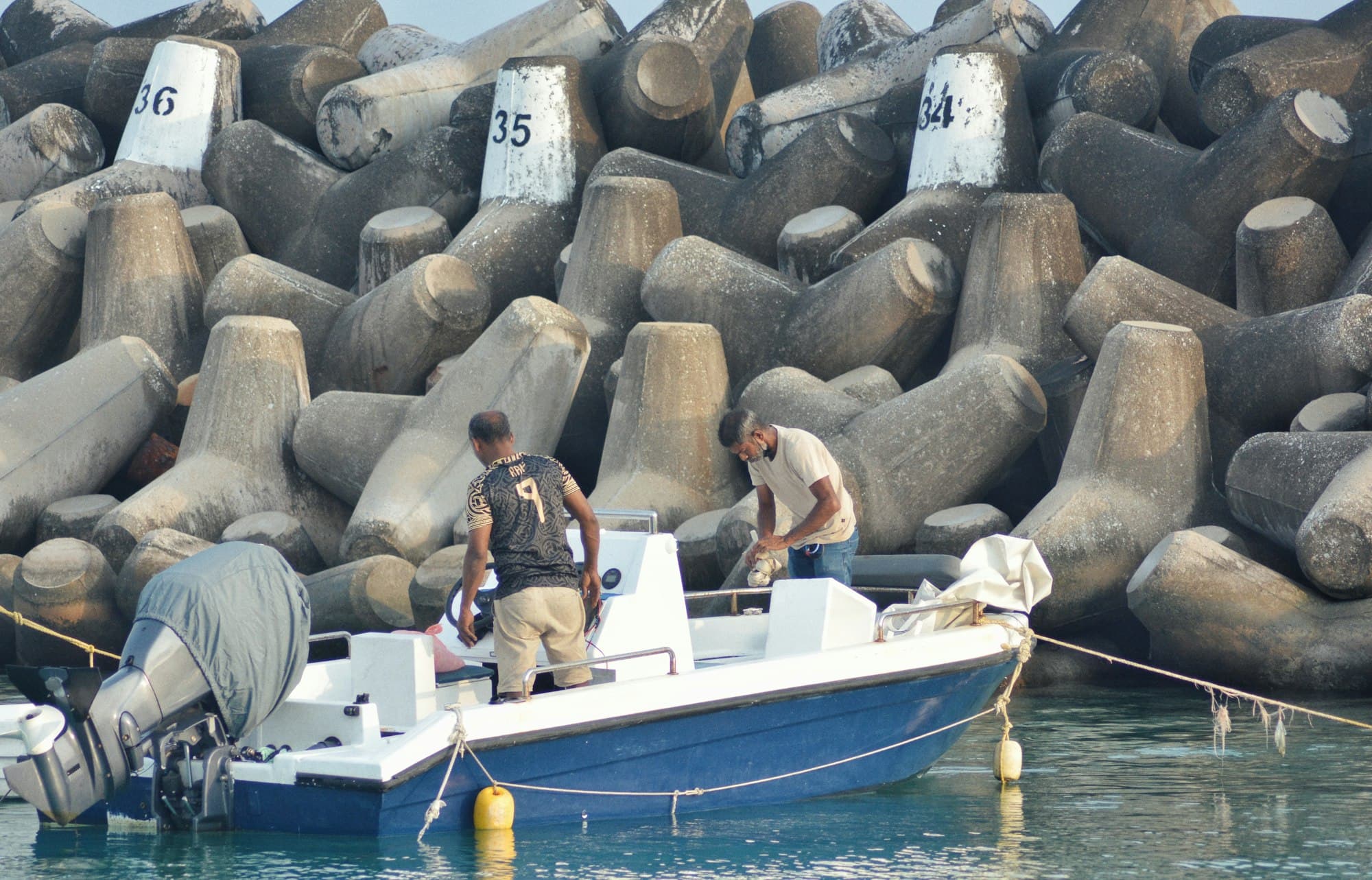 Two men at work on a boat in a harbour
